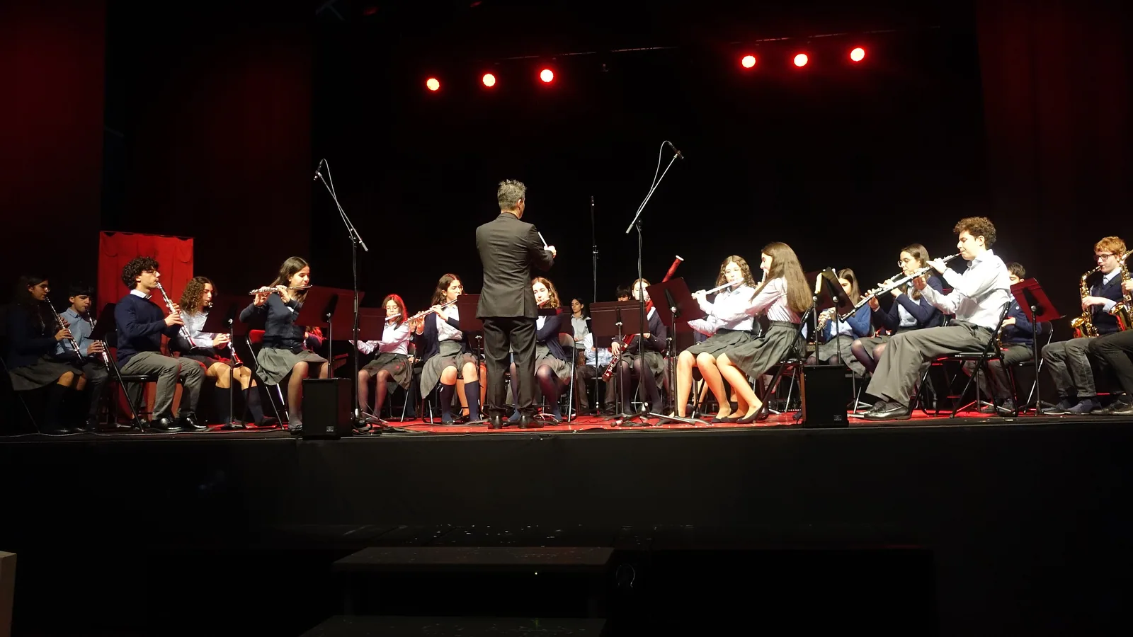 Julekonsert med skolekorps på en scene i rødt lys